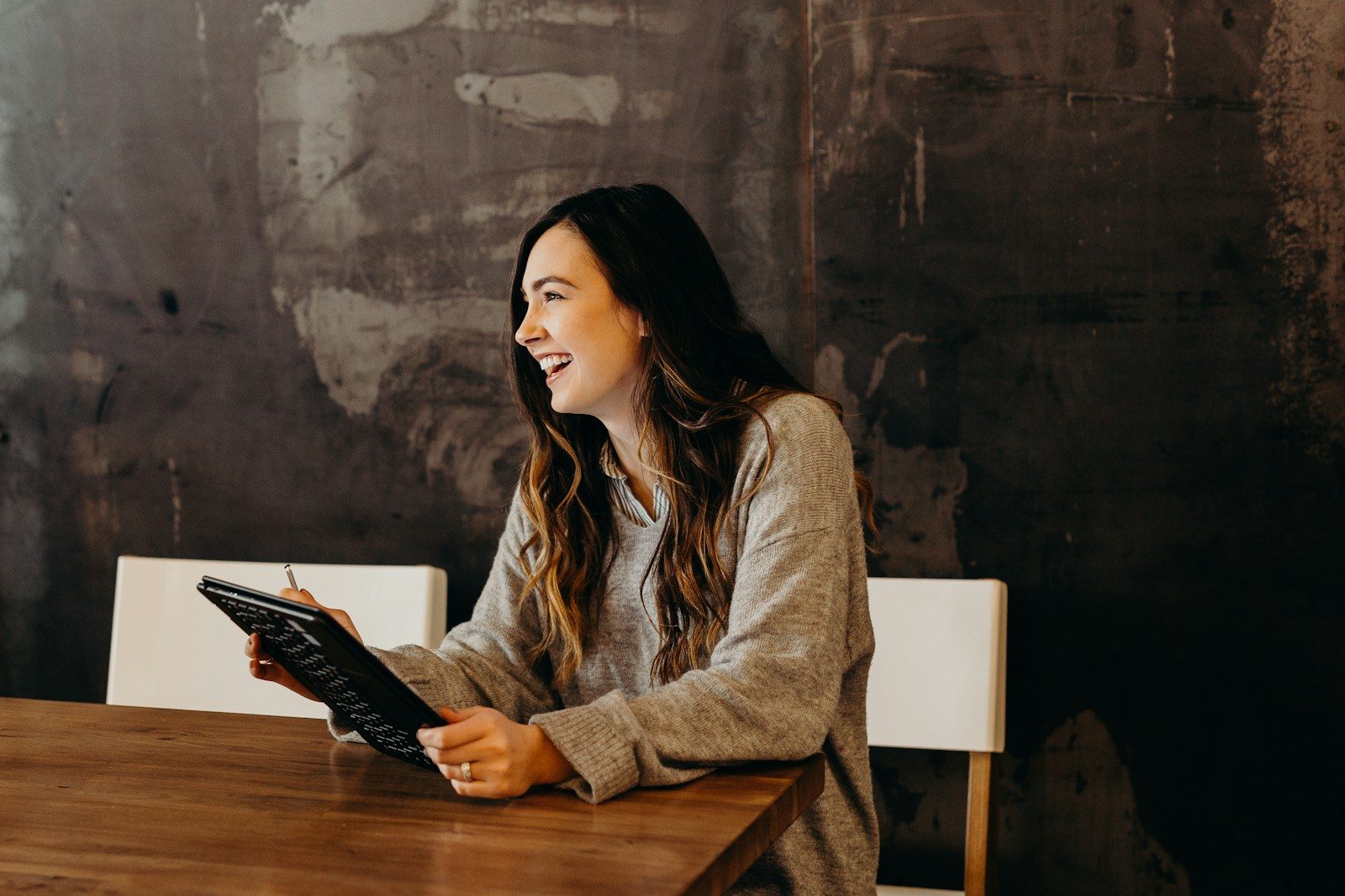 a woman sitting at a table holding a tablet